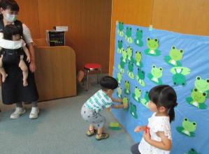 子どもたちがカエルの絵を貼る様子です。